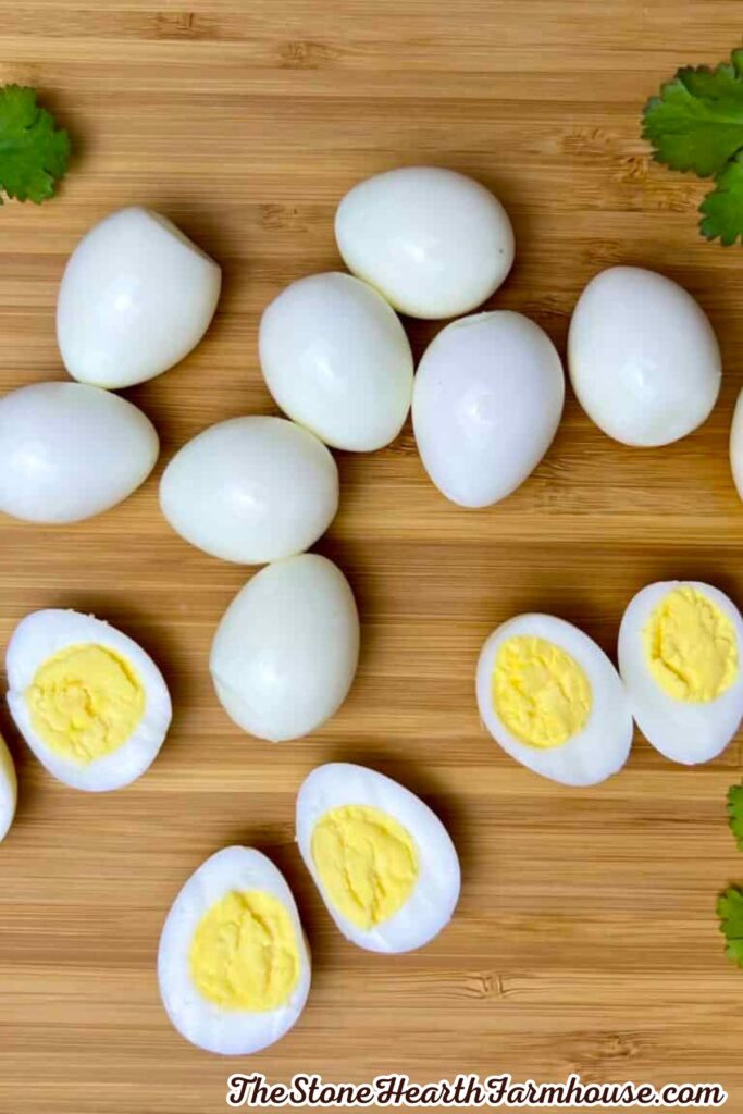 Halved quail eggs with firm yellow yolks displayed on a bamboo cutting board