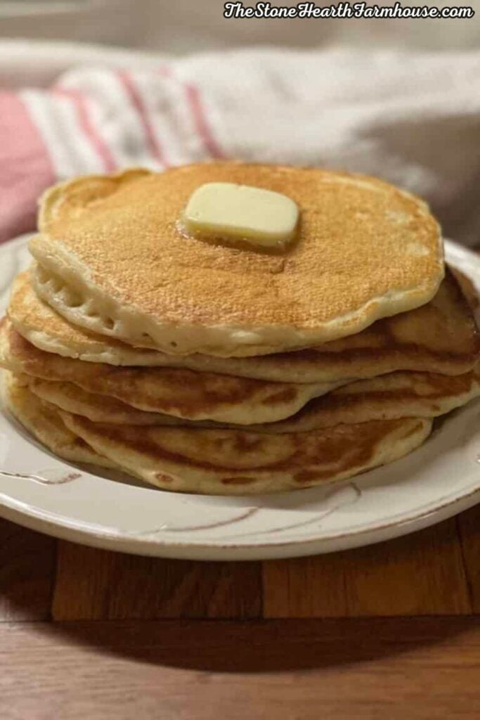 Stack of fluffy homemade sourdough discard pancakes topped with a pat of melting butter