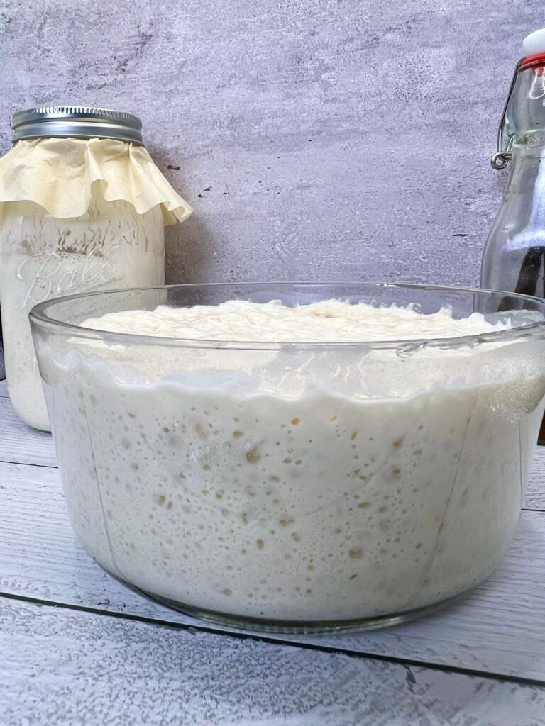 Side view of sourdough discard pancake batter fermenting in a glass bowl with visible air bubbles for light and fluffy pancakes.