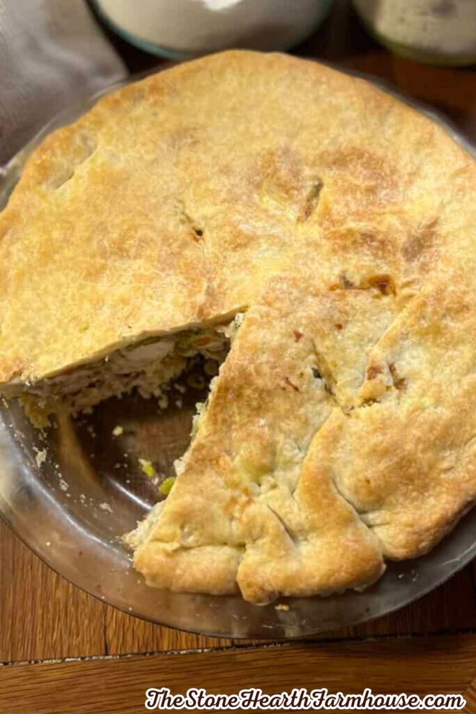 Golden brown rabbit pot pie with a flaky homemade crust, served in a glass pie dish with a slice removed
