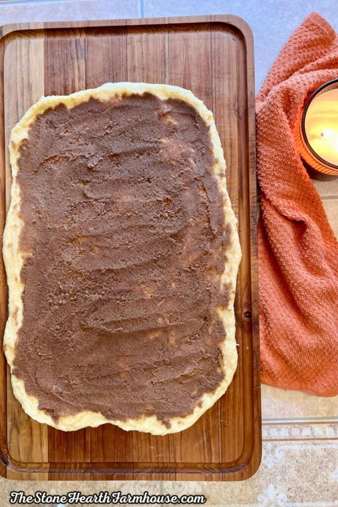 Cinnamon sugar filling spread evenly over rolled-out sourdough dough