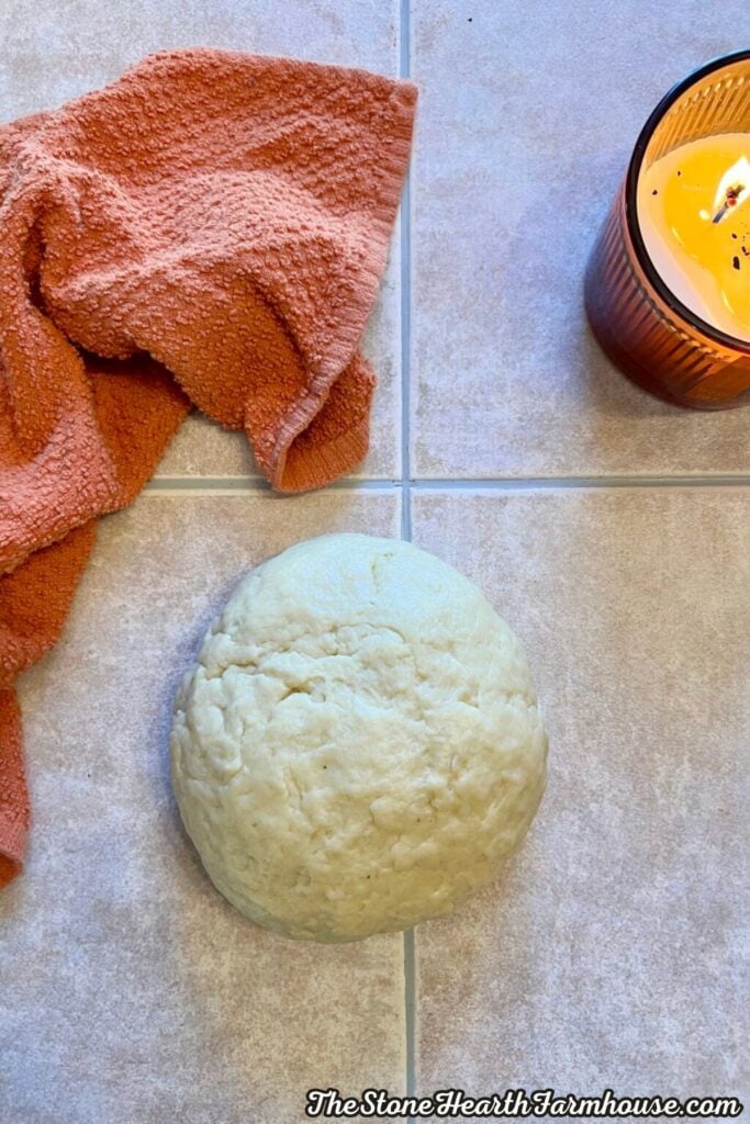 Homemade sourdough cinnamon roll dough formed into a ball on a kitchen counter