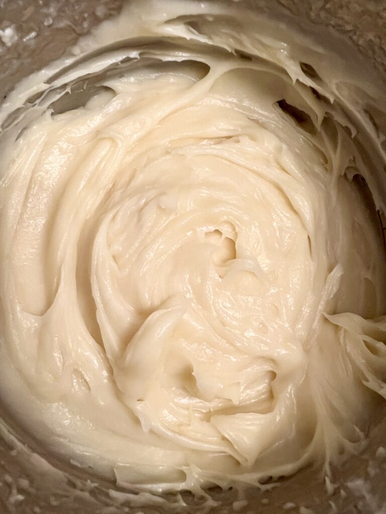 Smooth cream cheese frosting whipped until fluffy for topping sourdough cinnamon rolls.