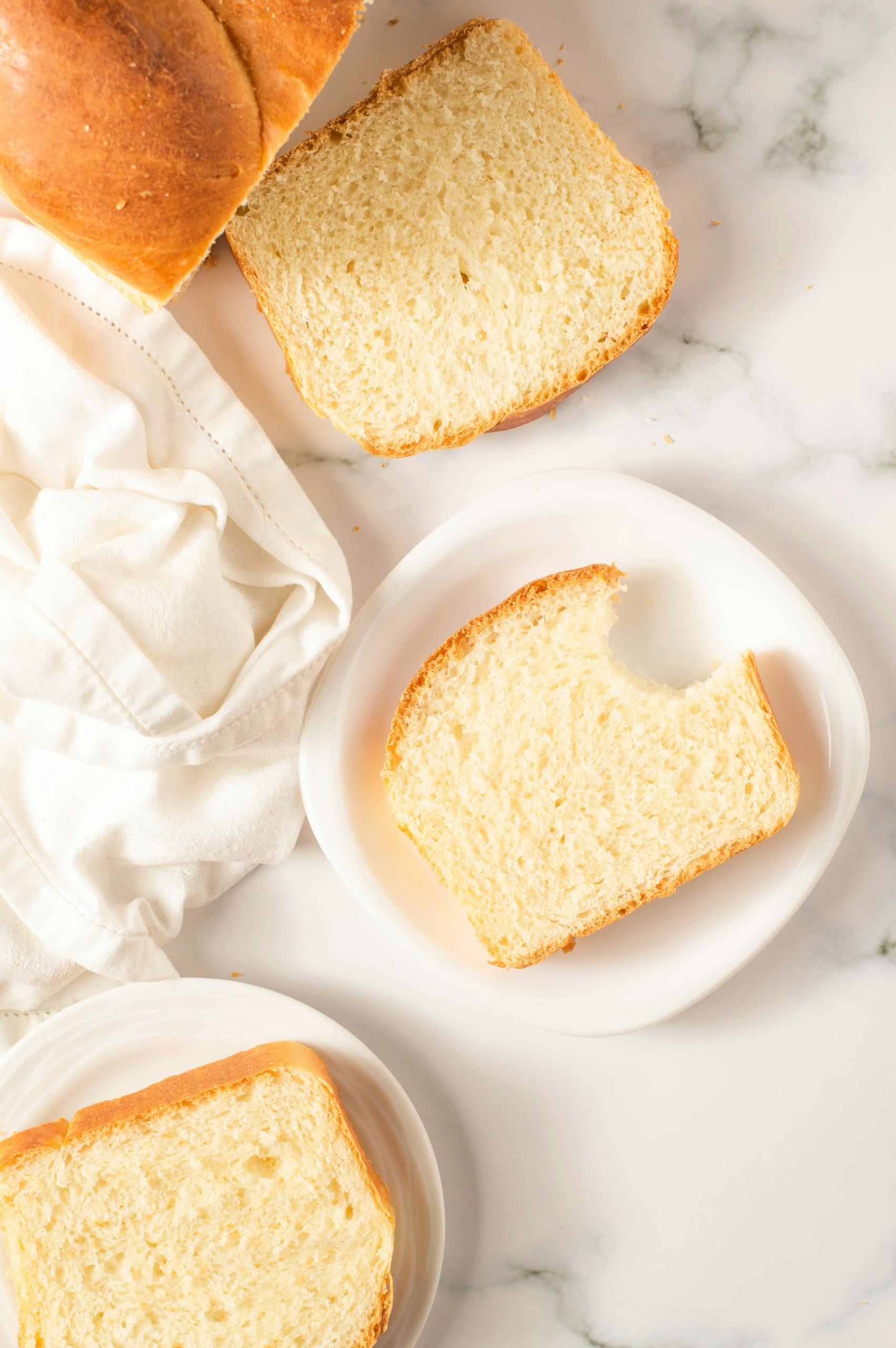 Close-up of sliced bread on white plates with a soft texture, ideal for bakery themed designs.