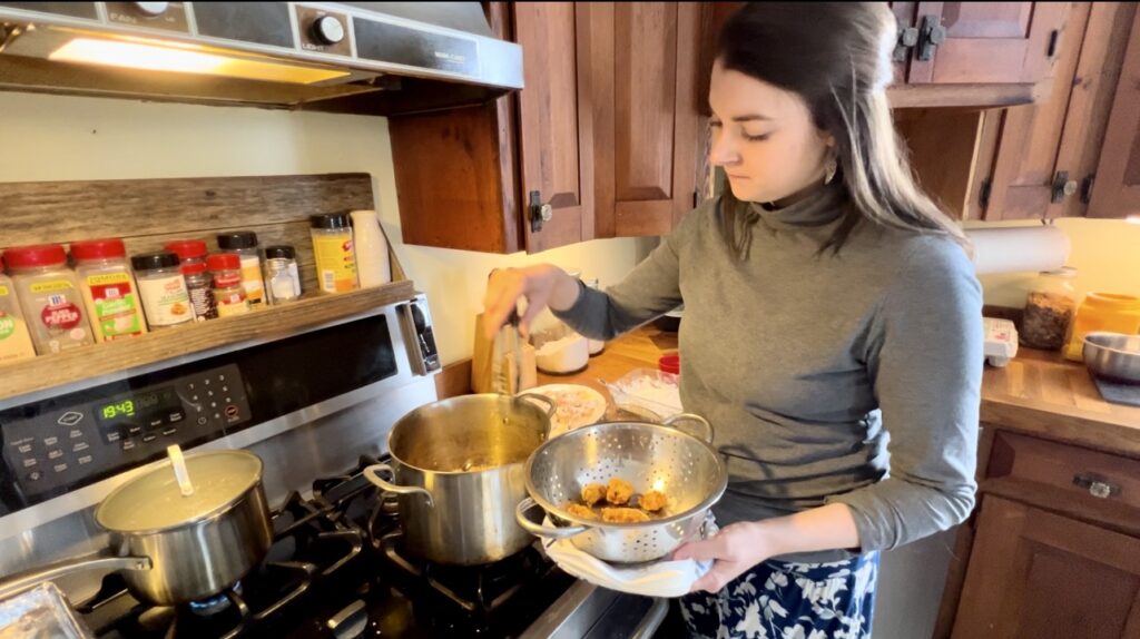 a women showing herself frying rabbit meat at her stove 