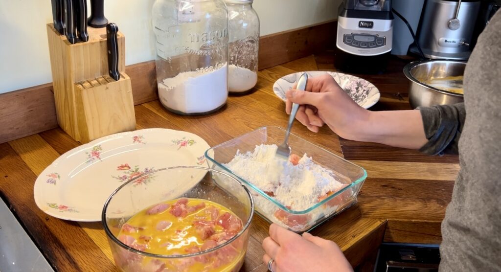 showing coating the rabbit meat in flour and them coating in egg wash. 