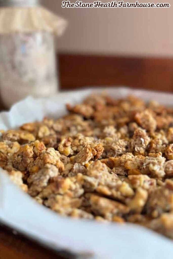 Homemade granola with oats, walnuts, pecans, and chocolate chips baked into crunchy clusters on a parchment-lined pan