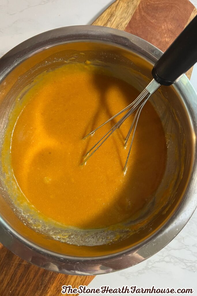 Pumpkin puree mixture whisked smooth in a stainless steel bowl before being added to the dry ingredients.