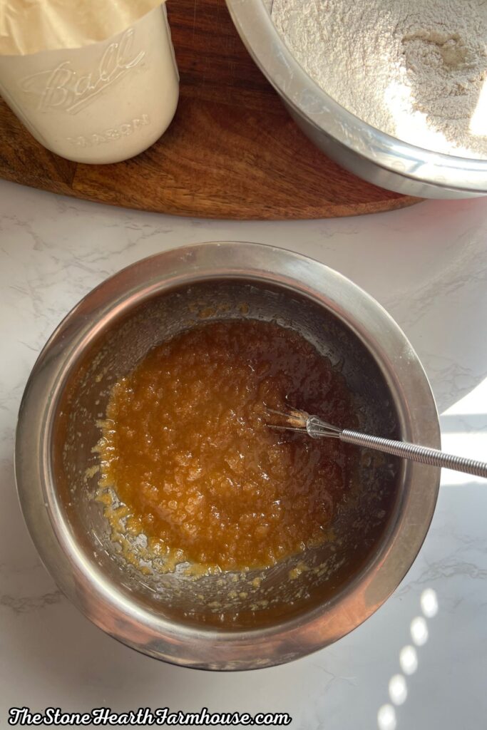 Wet banana bread ingredients combined in a mixing bowl adding brown sugar, white sugar, butter and eggs. 