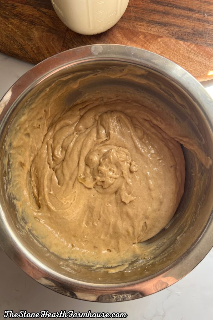 Smooth banana bread batter whisked together in a stainless steel mixing bowl
