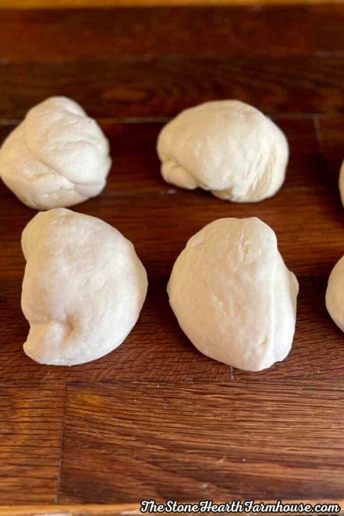 Portions of pretzel dough divided into individual pieces on a wooden countertop