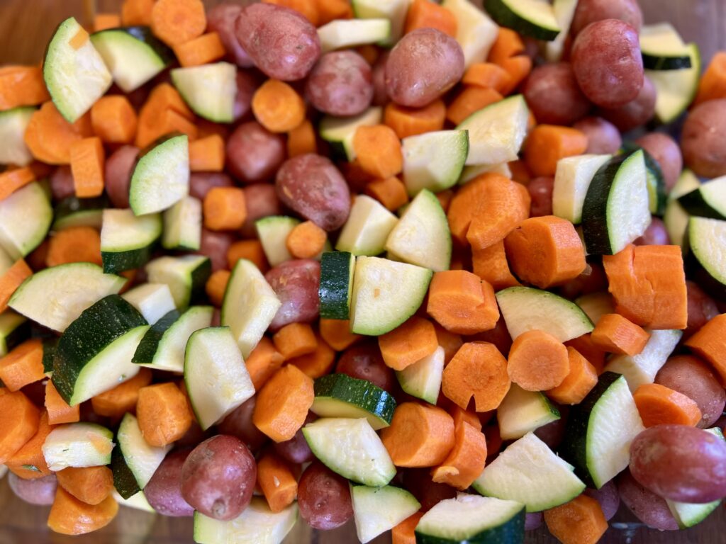 an up close picture of chopped vegetables. zucchini, carrots. and baby potatoes.