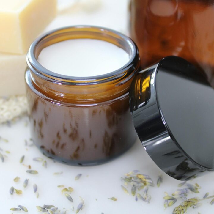 Delicate natural cream in amber glass jar, surrounded by lavender and beeswax, perfect for skincare routines.