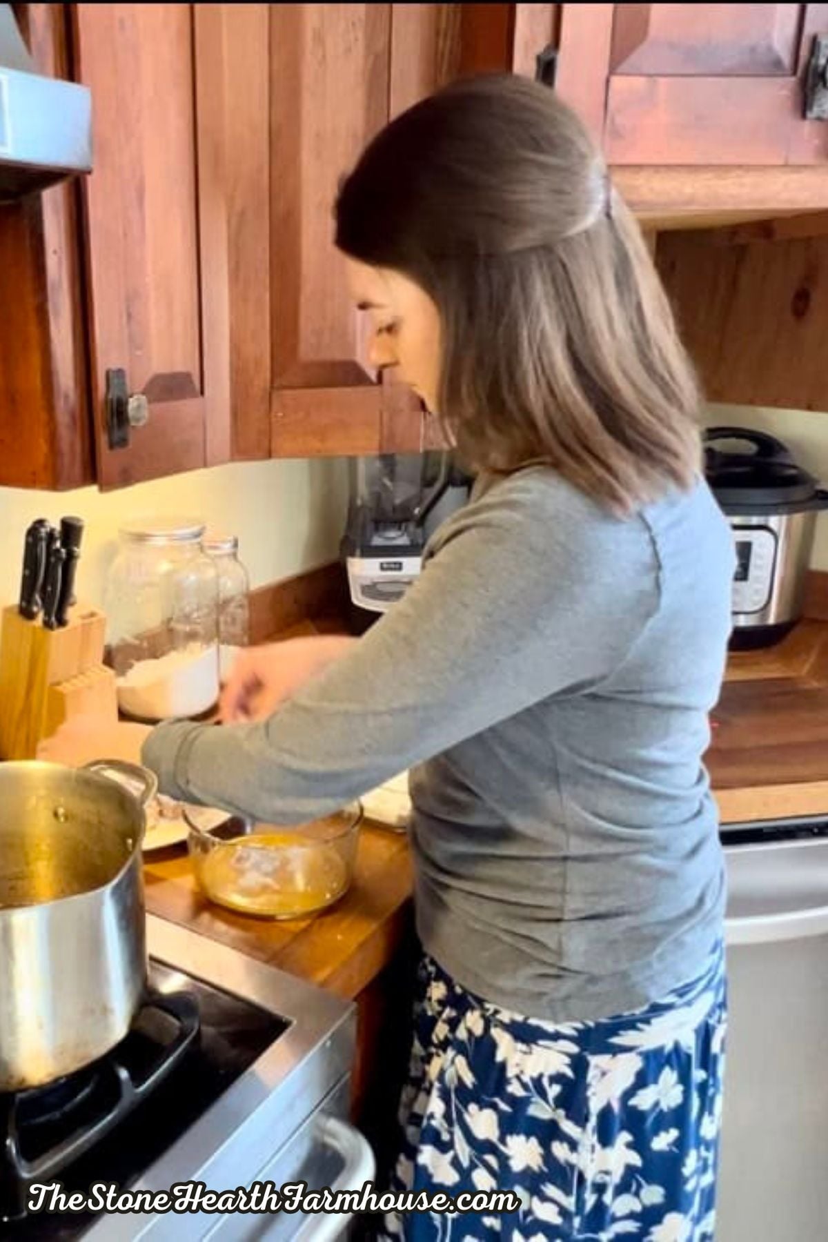 a women in her kitchen at the stove preparing rabbit meat in an egg wash to fry.