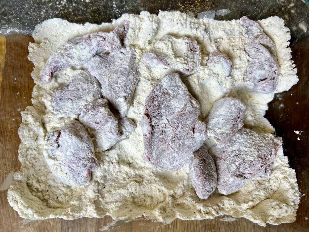 stew meat floured in a glass container, ready to be seared.