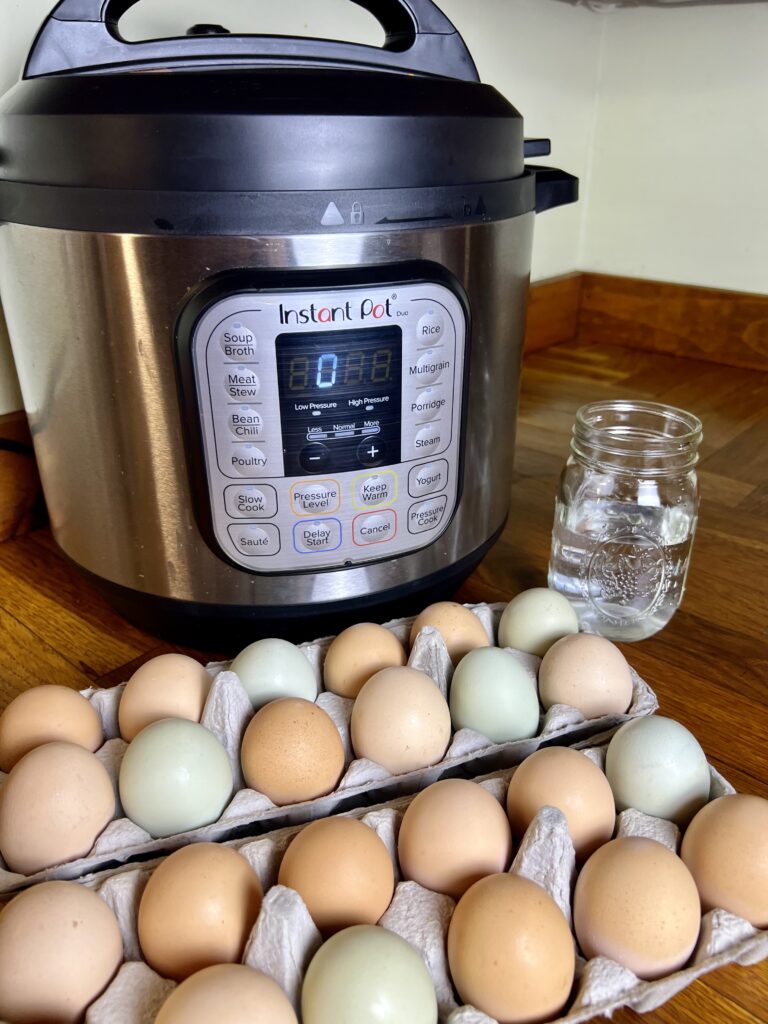 two open cartons of eggs next to a mason jar of water and pressure cooker in the back round.