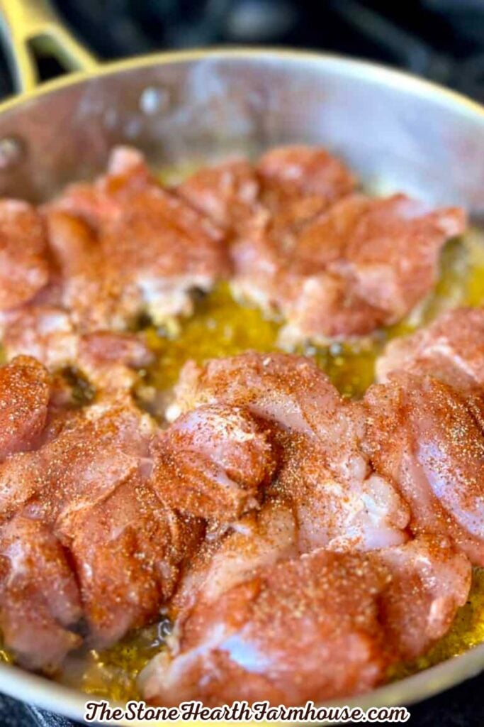 Seasoned rabbit pieces cooking in a skillet with olive oil before being added to the creamy sauce