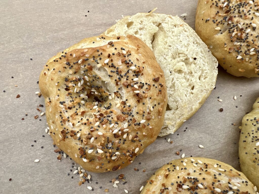 A sourdough bagel with everything bagels seasoning on it. sliced in half.