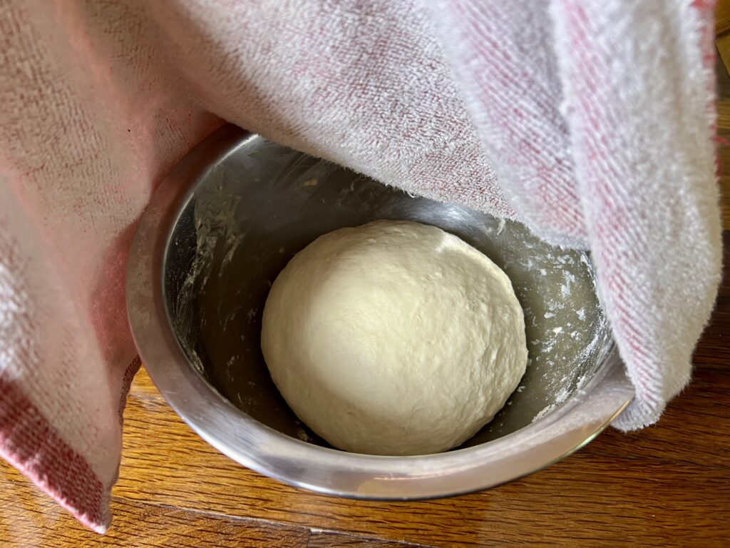 fermented dough in a bowl ready to sit over night with a towel over it.