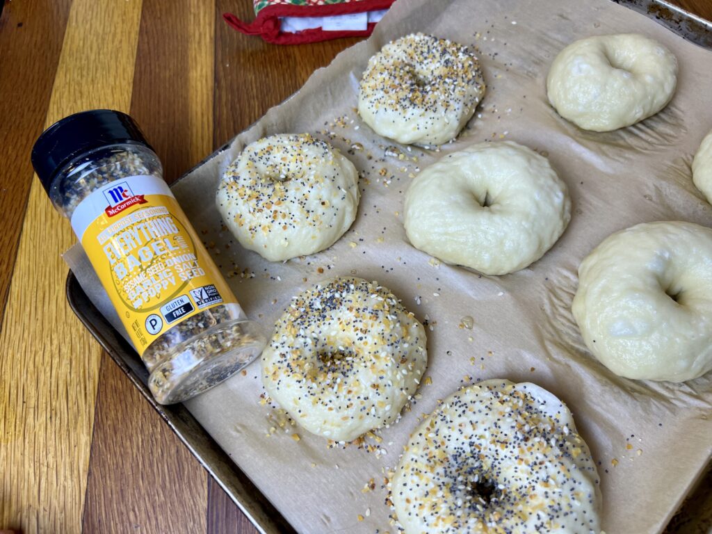 bagels on a baking sheet, with everything bagel seasoning next to them.