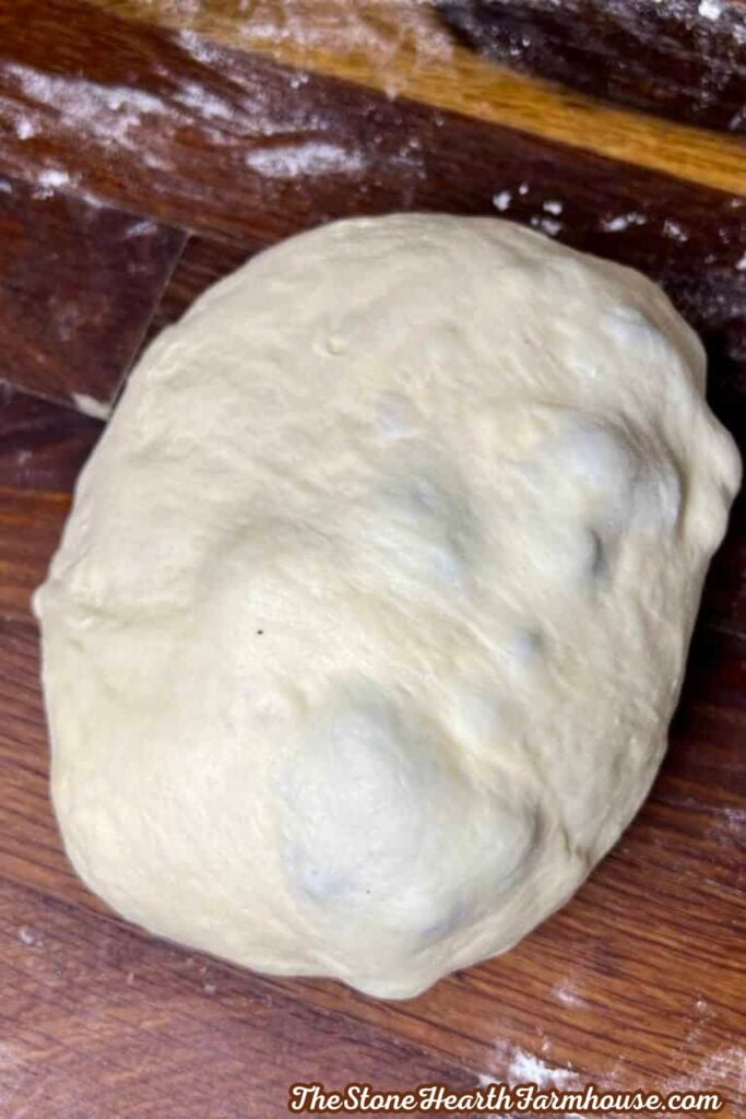 dough on a wooden counter ready to be shaped into individual bagels. 