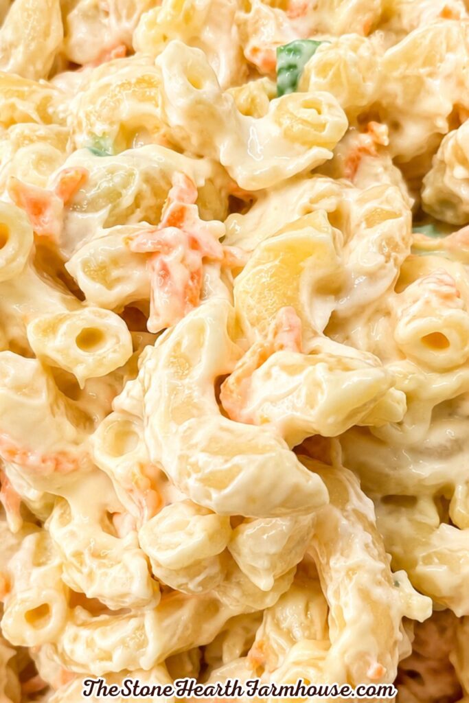 Close-up of creamy homemade macaroni salad with tender pasta, shredded carrots, green onion, and a smooth mayonnaise dressing
