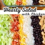 Hearty chicken salad with grilled chicken, rice, black beans, lettuce, tomatoes, and shredded cheese in a glass baking dish.
