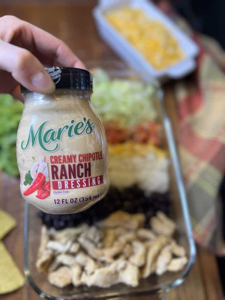 a hand holding the dressing container for Marie's creamy chipotle ranch dressing.