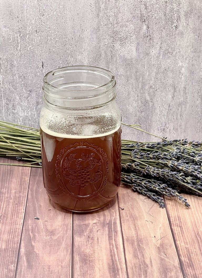 A jar of beer with a bunch of lavender.