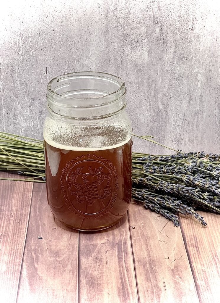A jar of honey and lavender on a wooden table.