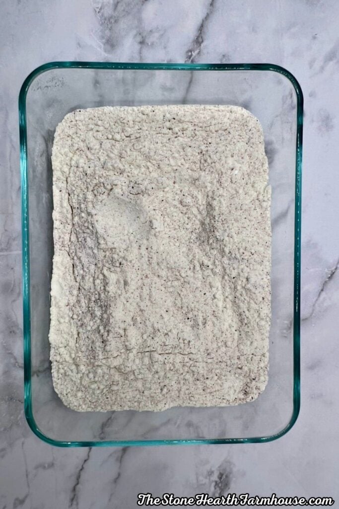 Seasoned flour mixture prepared for coating chicken breasts for a crispy fried chicken sandwich