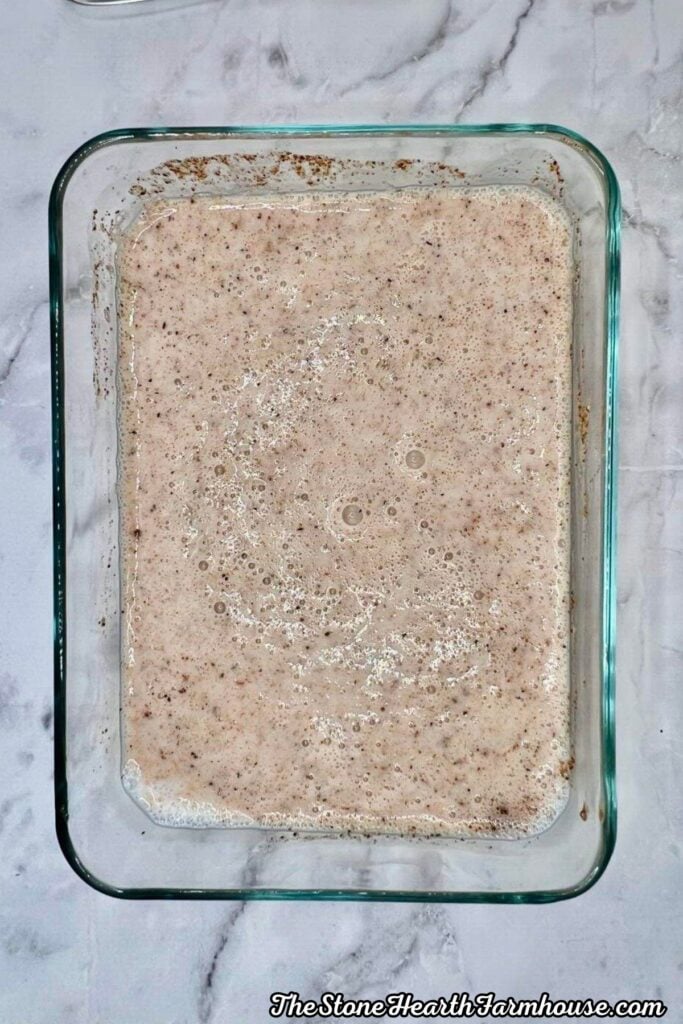 Seasoned buttermilk mixture spread in a baking dish for coating chicken before frying