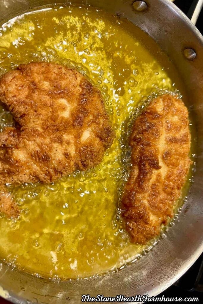 Crispy buttermilk fried chicken pieces cooking in hot oil until golden brown