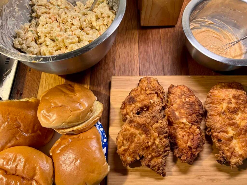 Crispy buttermilk fried chicken sandwich with lettuce, pickles, and creamy sauce served with creamy pasta salad