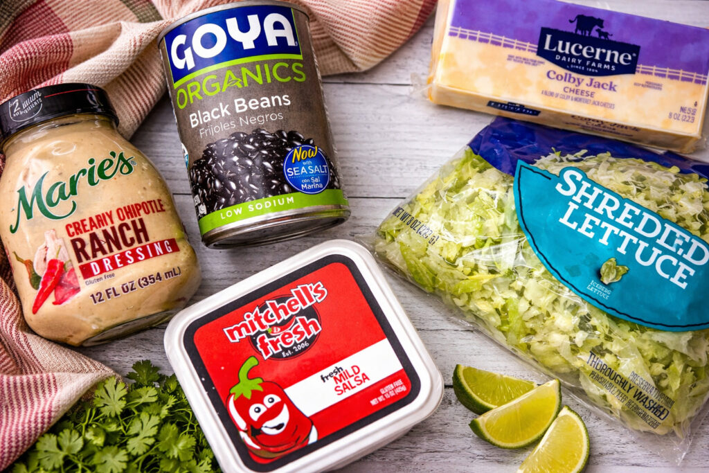 shows ingredients for southwest Chicken salad, creamy chipotle ranch dressing, black beans, cheese, lettuce, and salsa. 