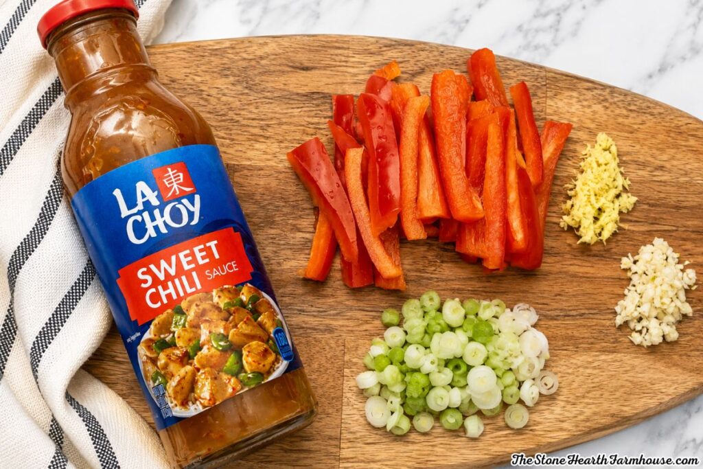 Ingredients for sweet chili rabbit including sliced red bell pepper, green onions, garlic, ginger, and sweet chili sauce