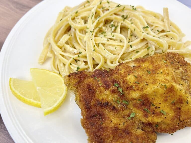 A plate with a chicken cutlet and pasta.