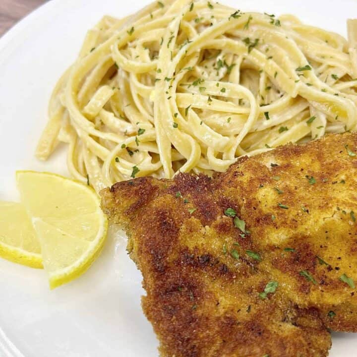 A plate with a chicken cutlet and pasta.