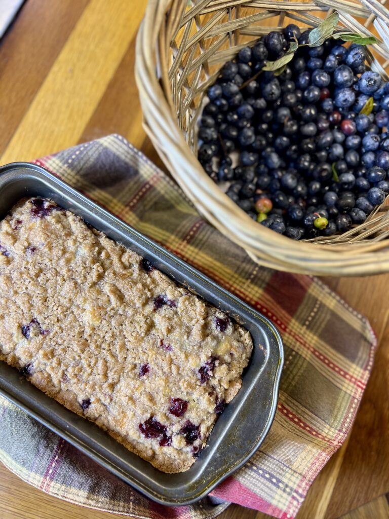 blueberry tea cake displayed next to a basket of blueberries.
