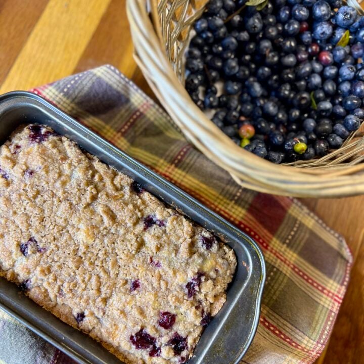blueberry tea cake displayed next to a basket of blueberries.