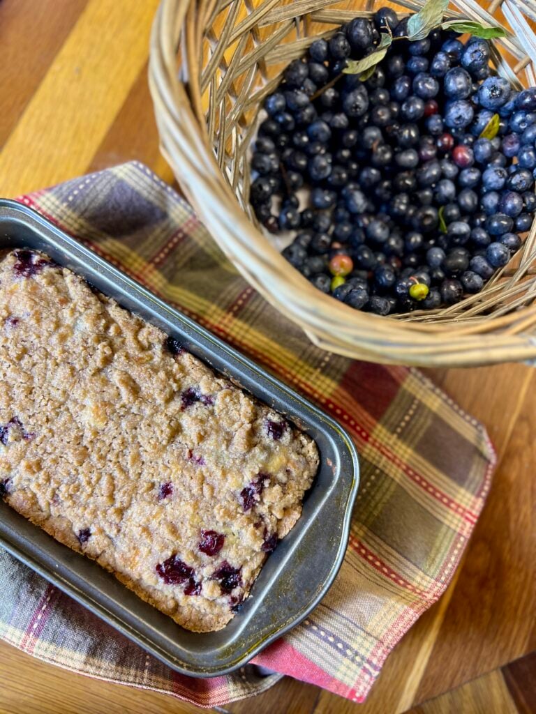 blueberry tea cake displayed next to a basket of blueberries.