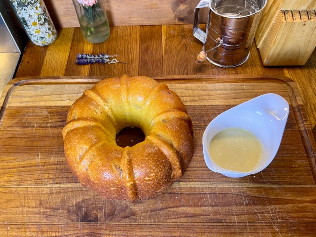 apple Bundt cake fresh out of the oven. takian out of the Bundt pan and cooling with glaze next to it.