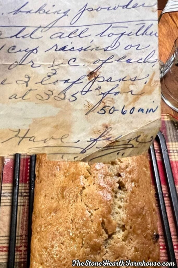 Handwritten family recipe beside a loaf of homemade zucchini bread with raisins, showing the traditional recipe notes and finished bread.