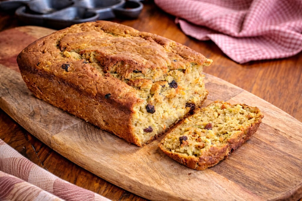 carrot and zucchini bread sliced on a wooden cutting board to show the inside of the loaf. 
