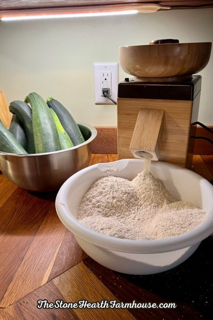 Fresh wheat berries milled into flour beside garden zucchini, ingredients for homemade whole grain quick bread.