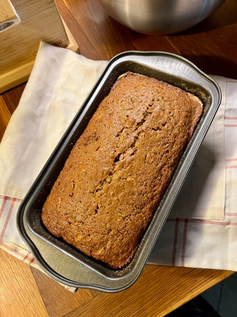 A healthy zucchini bread loaf set on top of a red and white towel. Fresh out of the oven. 
