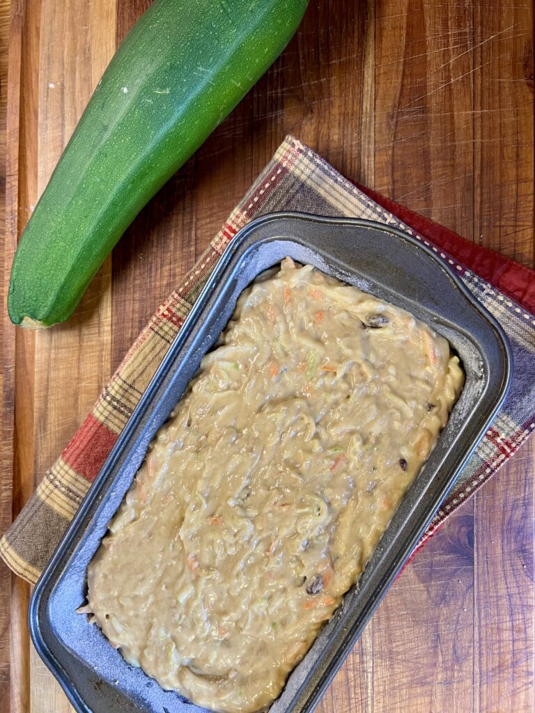 Carrot and Zucchini bread batter inside a loaf pan, ready to be put into the oven.