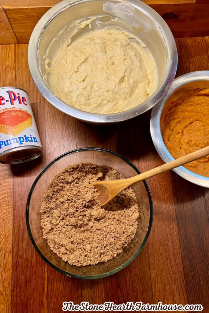 Ingredients for a homemade pumpkin cake including pumpkin puree, flour mixture, brown sugar, and prepared batter.