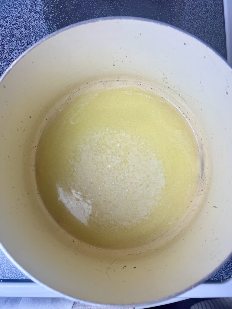 Melted butter in a large pot on the stovetop, the first step in making Christmas Rice Krispie wreath treats.