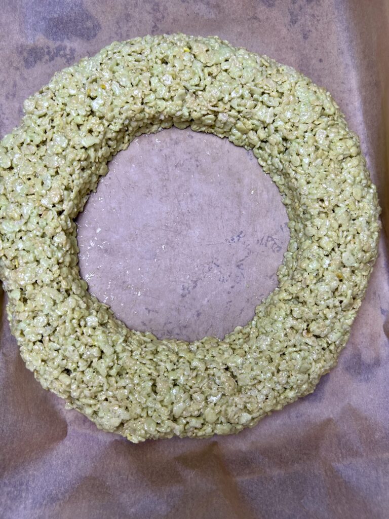 Large Christmas Rice Krispie wreath formed into a thick ring shape on parchment paper.